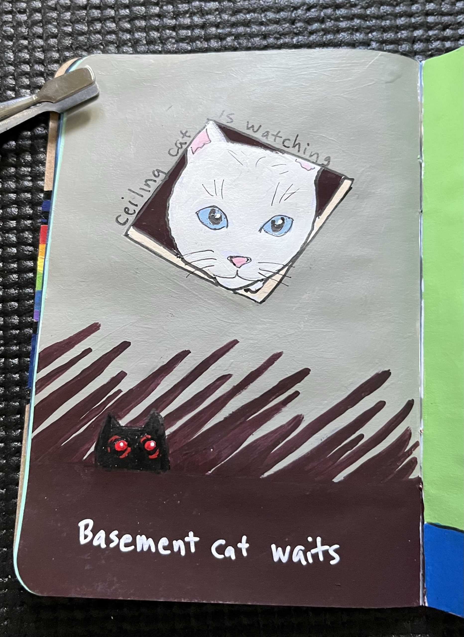A painted benevolent white cat, pokes his head through a hole in the ceiling. A painted black cat with red eyes, stalks from below