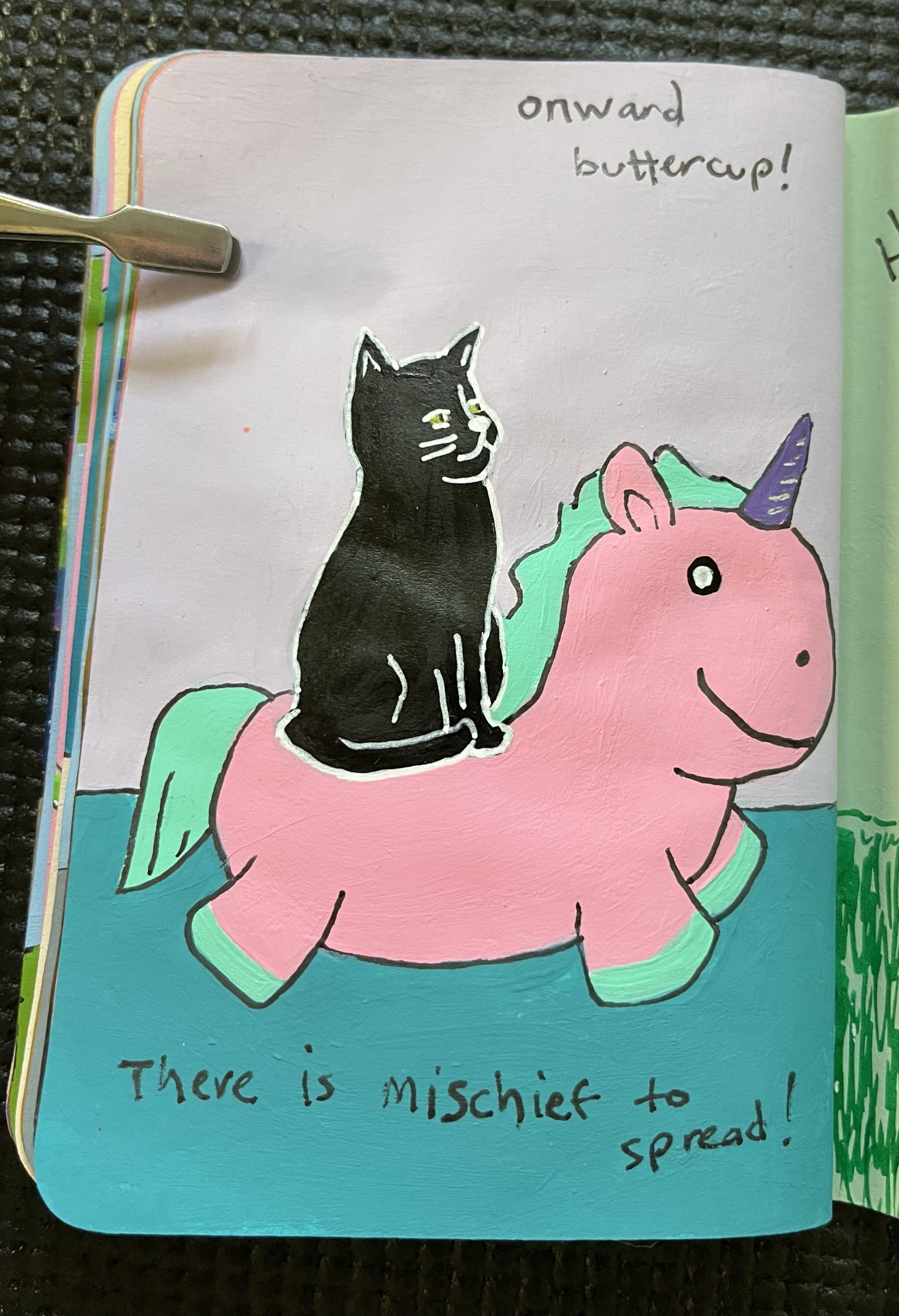 A painted page showing a mischievous kitten on a unicorn stuffed animal.